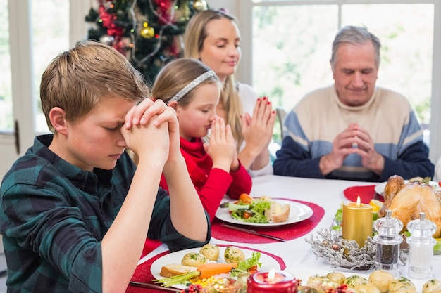 Famille élargie disant grâce avant le dîner de Noël