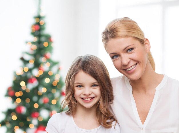 famille, enfance, vacances et personnes - mère souriante et petite fille sur fond de salon et d'arbre de noël