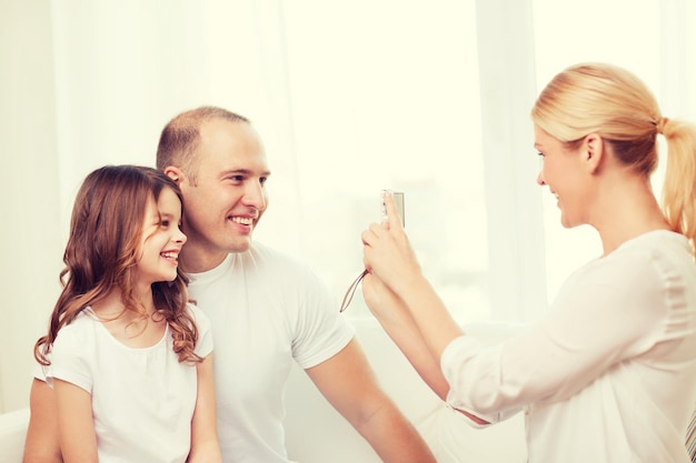 famille, enfant, photographie et concept de maison - mère heureuse souriante prenant une photo du père et de la fille