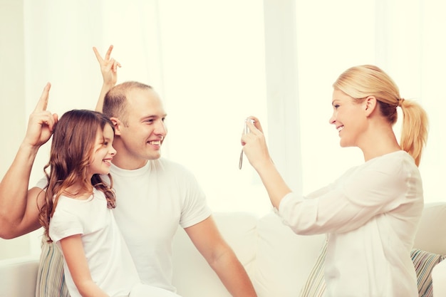 famille, enfant, photographie et concept de maison - mère heureuse souriante prenant une photo du père et de la fille