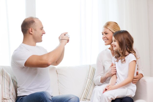 famille, enfant, photographie et concept de maison - père souriant et heureux prenant une photo de la mère et de la fille