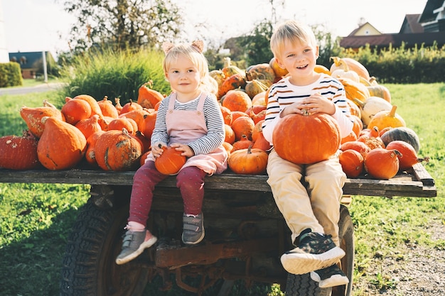 Famille Et Enfants à L'automne Enfants D'âge Préscolaire Assis Dans Des Tas De Citrouilles Au Marché Agricole Local