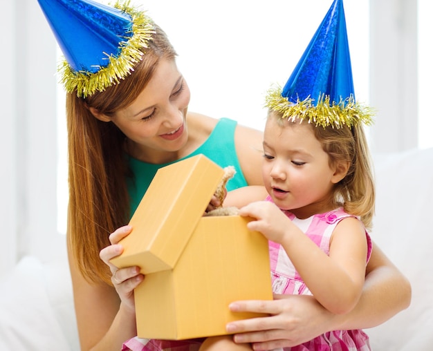 famille, enfants, célébration, vacances, anniversaire et concept de personnes heureuses - heureuse mère et fille en chapeaux bleus avec boîte-cadeau