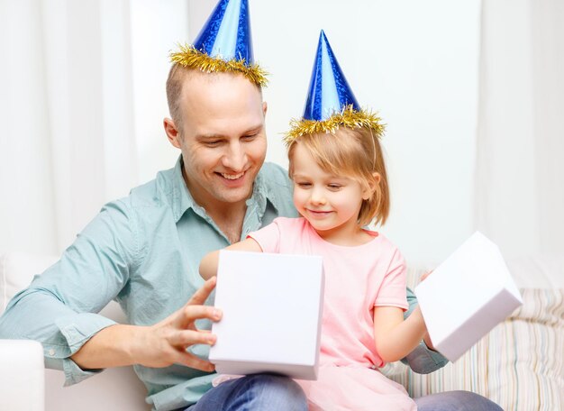 famille, enfants, célébration, vacances, anniversaire et concept de personnes heureuses - heureux père et fille en chapeaux de fête bleus avec boîte-cadeau