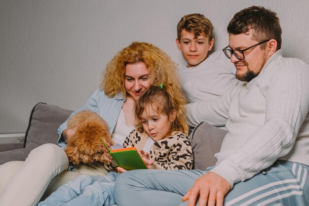 Famille avec enfants et un chien à la maison sur le canapé planifiant une entreprise commune vérifiant le calendrier