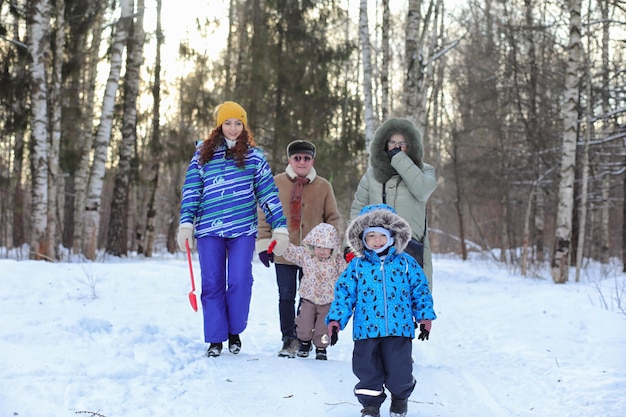 Famille avec enfants dans le parc d'hiver le week-end enneigé