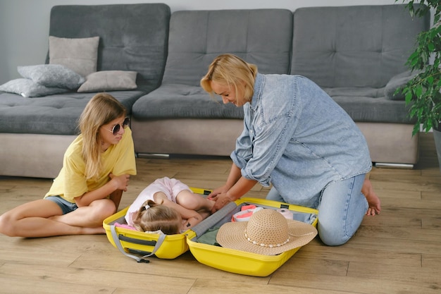 Une famille avec des enfants emballant une valise jaune pour voyager avec plaisir