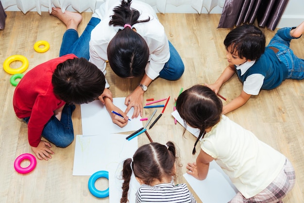 Famille enfants heureux groupe enfant garçon et fille maternelle peinture dessin sur la formation des enseignants peper à la salle de jeux intérieure