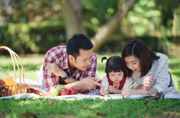 Famille avec enfants profitant d'un pique-nique dans le jardin de printemps Parents et enfants s'amusant à déjeuner à l'extérieur dans le parc d'été Mère et père et fille jouant du ukulélé dans le jardin