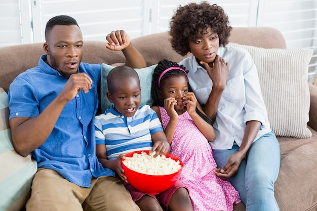 Famille et enfants regardant la télévision tout en ayant du pop-corn dans le salon
