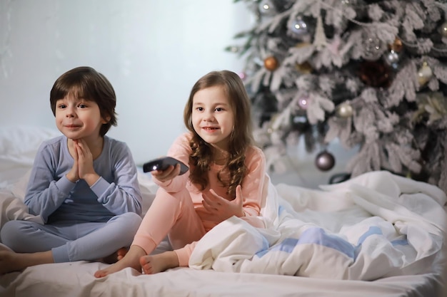 Une famille avec des enfants s'amusant sur le lit sous les couvertures pendant les vacances de Noël.