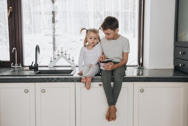 La famille est assise à la fenêtre et regarde la forêt d'hiver. Bon esprit du nouvel an. Matin en pyjama.