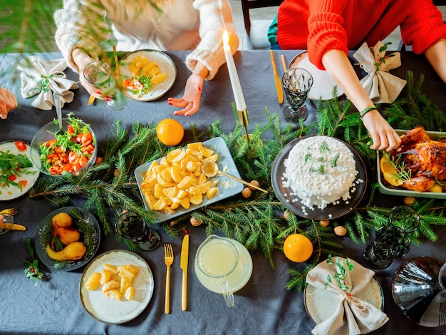 La famille est assise à la table de Noël pleine de nourriture