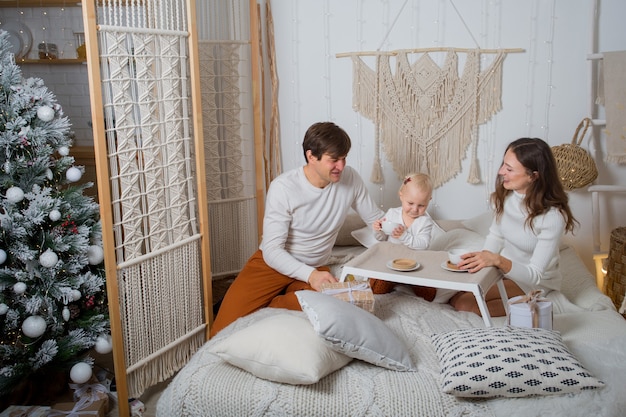 Famille européenne prendre le petit déjeuner dans le lit avec des cadeaux