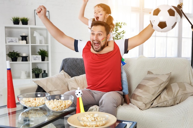 Famille de fans regardant un match de football à la télévision à la maison