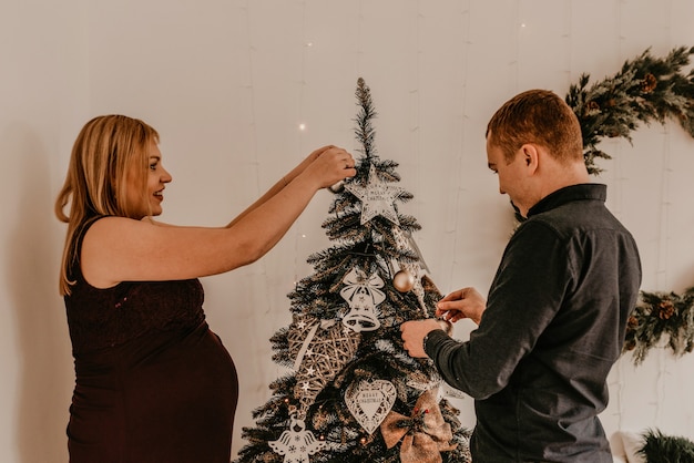 Famille avec femme enceinte décore la maison pour le nouvel an. Matin de noël. intérieur. Célébration de la Saint-Valentin