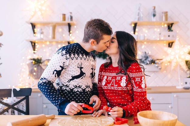 Famille femme et homme préparant des biscuits le soir de Noël dans une cuisine lumineuse