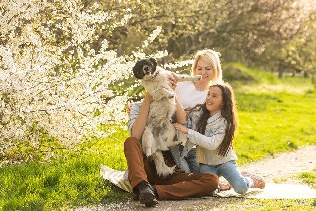 Famille avec fille et chien jouent ensemble dans le jardin au printemps