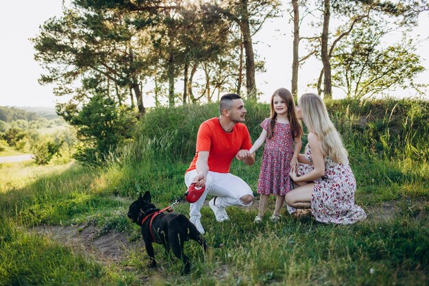 Famille avec fille et chien jouent ensemble dans le jardin en été