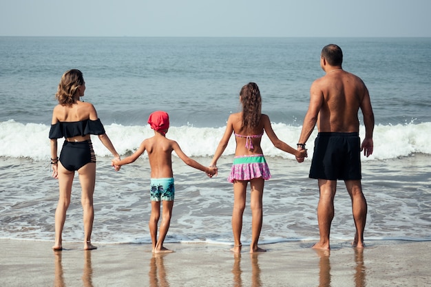 Une famille forte se promène le long de la plage de l'arrière