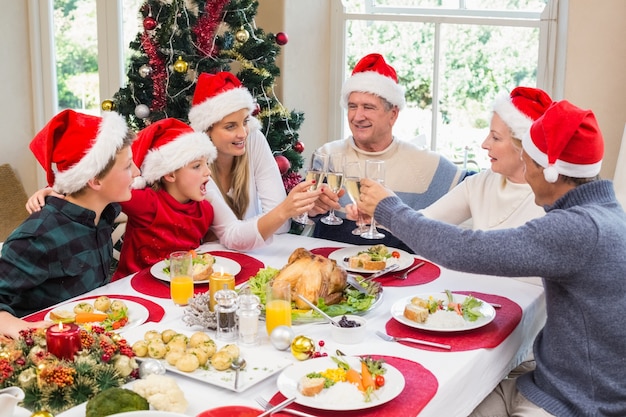 Famille de génération multiple en chapeau de père Noël portant un toast