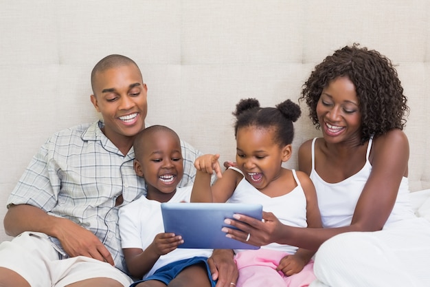 Famille heureuse à l&#39;aide de tablette ensemble sur le lit