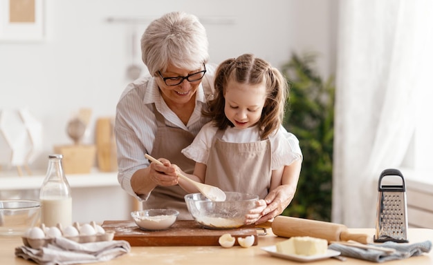 Une famille heureuse et aimante prépare une boulangerie ensemble Mamie et son enfant préparent des biscuits et s'amusent dans la cuisine