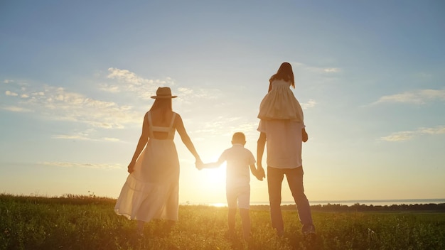 Une famille heureuse aime marcher ensemble sur un pré contre le ciel