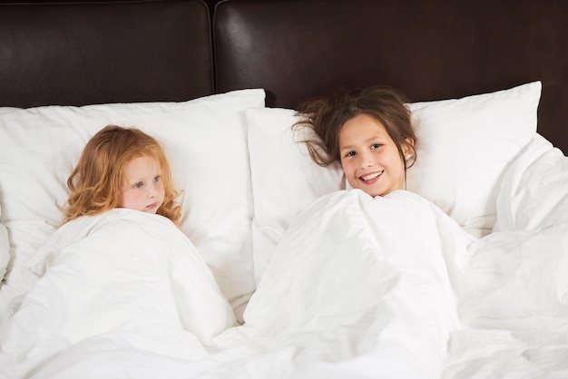 Famille heureuse allongée sous une couverture au lit à la maison