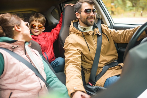 Famille heureuse et amicale voyageant en voiture sur une route rurale