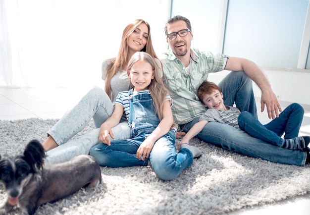 Famille heureuse avec animal de compagnie assis sur le tapis