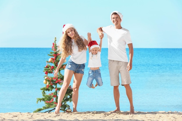 Famille heureuse et arbre de Noël sur la plage