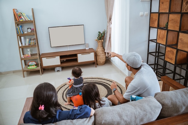 Famille heureuse asiatique assis sur un canapé à la maison, regarder la télévision ensemble