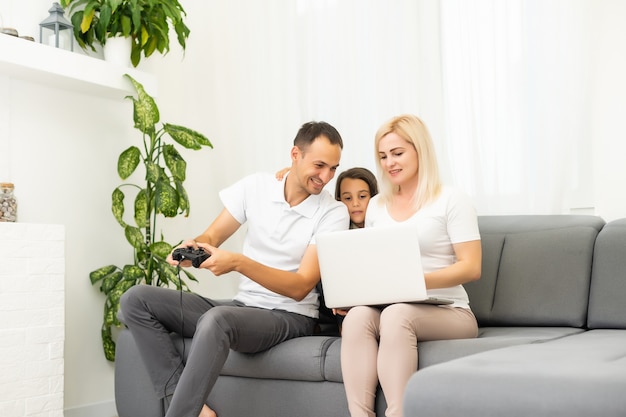 Famille heureuse assise sur un canapé et jouant à des jeux vidéo.