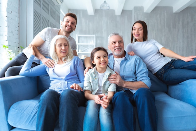 La famille heureuse assise sur le canapé