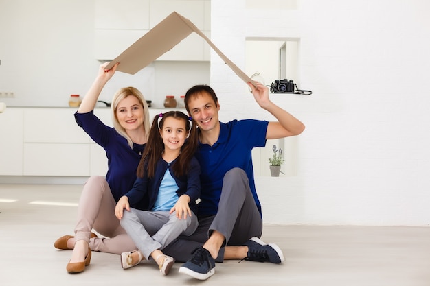 famille heureuse assise ensemble et faisant le signe de la maison