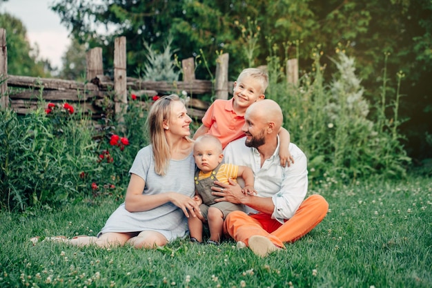 Photo une famille heureuse assise sur l'herbe dans le parc.