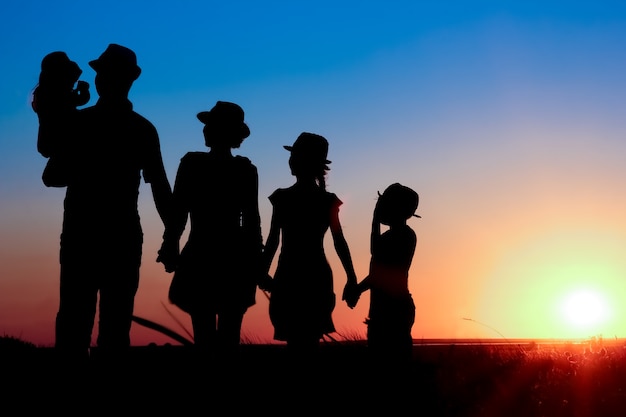 Photo une famille heureuse au bord de la mer au coucher du soleil en silhouette de voyage dans la nature