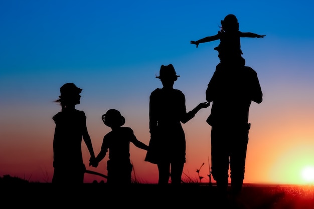 Une famille heureuse au bord de la mer au coucher du soleil en silhouette de voyage dans la nature