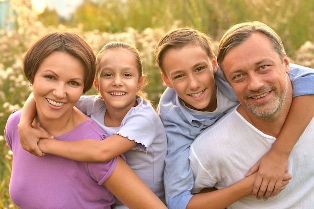 Famille heureuse au champ de floraison vert d'été