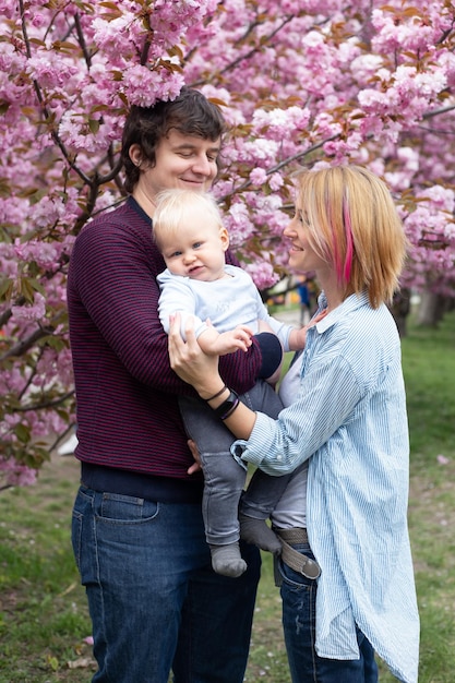 Famille heureuse au parc de printemps Petit garçon et parents s'amusent le week-end dans les jardins fleuris de Sakura