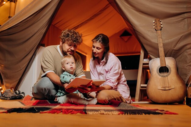 Famille heureuse avec un beau bébé jouant et passant du temps ensemble dans le glamping le soir d'été Tente de camping de luxe pour les loisirs de plein air et les loisirs Concept de style de vie