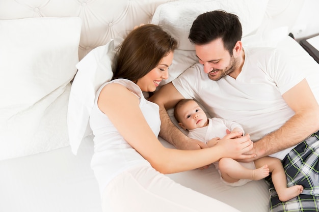 Famille heureuse avec bébé nouveau-né sur le lit dans la chambre