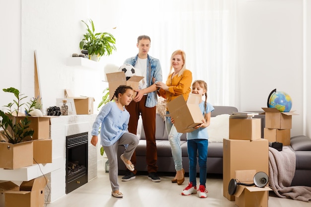 Famille heureuse avec des boîtes en carton dans la nouvelle maison le jour du déménagement.