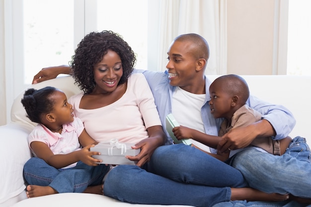 Famille heureuse sur le canapé en donnant des cadeaux de mère