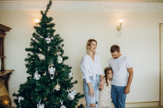 Famille heureuse en chapeaux de Père Noël près de l'arbre de Noël à la maison