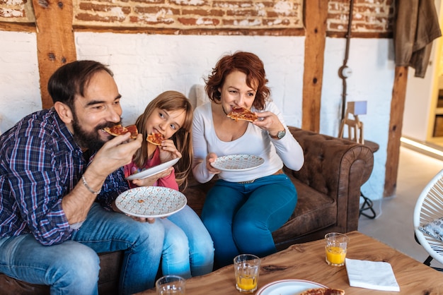 Famille heureuse, chez soi, divan, pizza mangeant