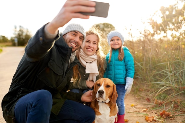 famille heureuse avec un chien prenant un selfie en automne