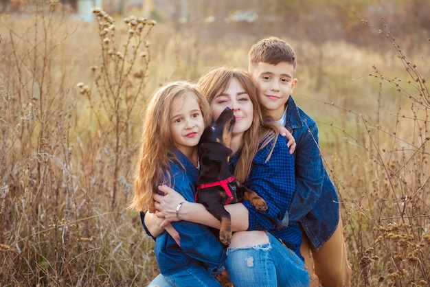 Famille heureuse avec un chien teckel dans le parc d'automne