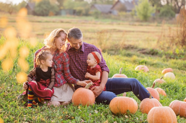 Famille heureuse avec des citrouilles orange dans le champ d'automne